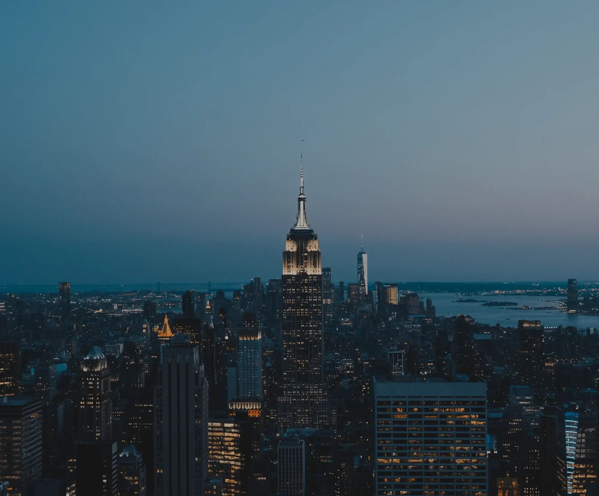 Panoramic shot of Manhattan, Empire State Building glowing after sunset.