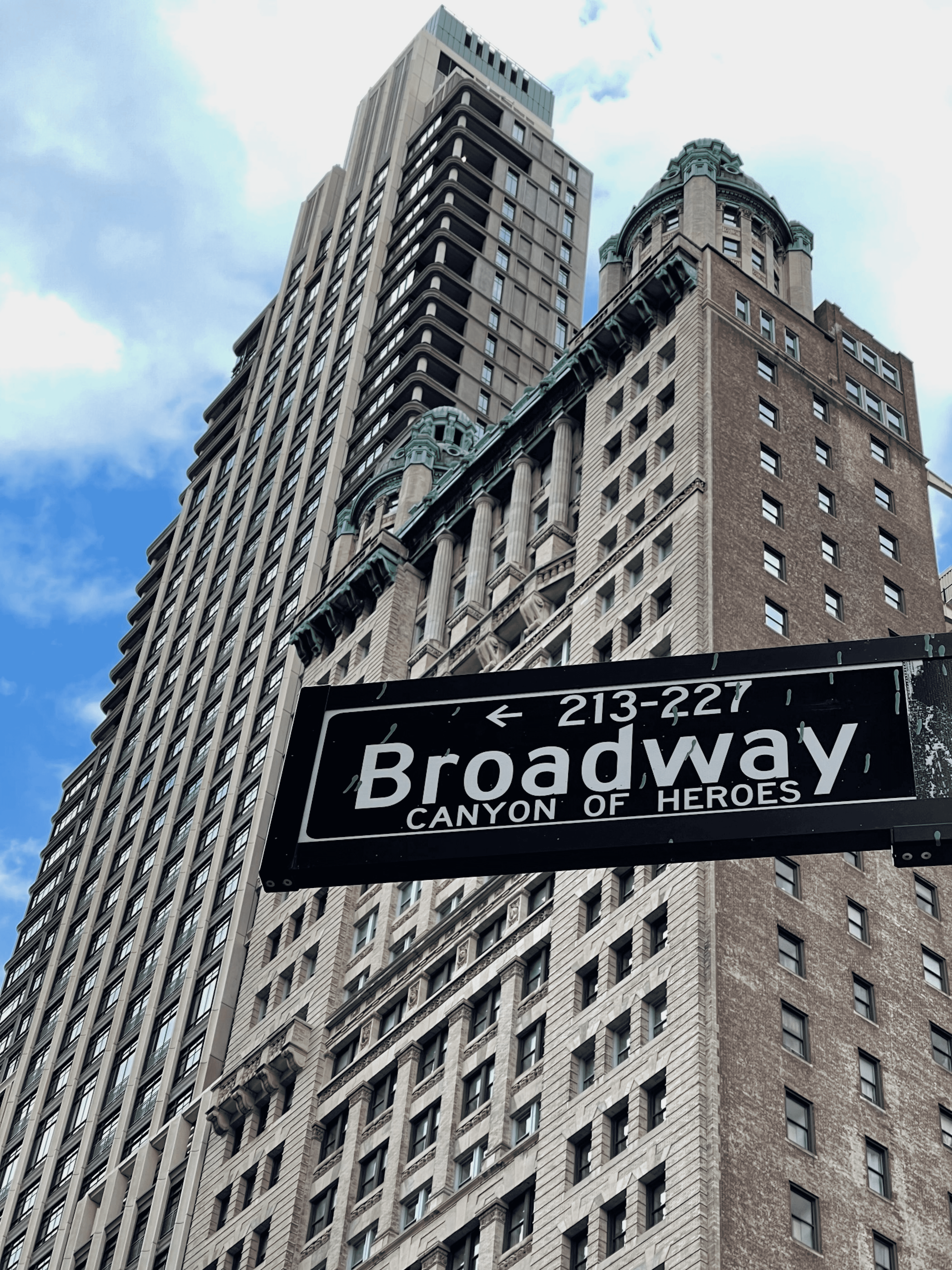 A New York City building, with the Broadway street sign in front of it.